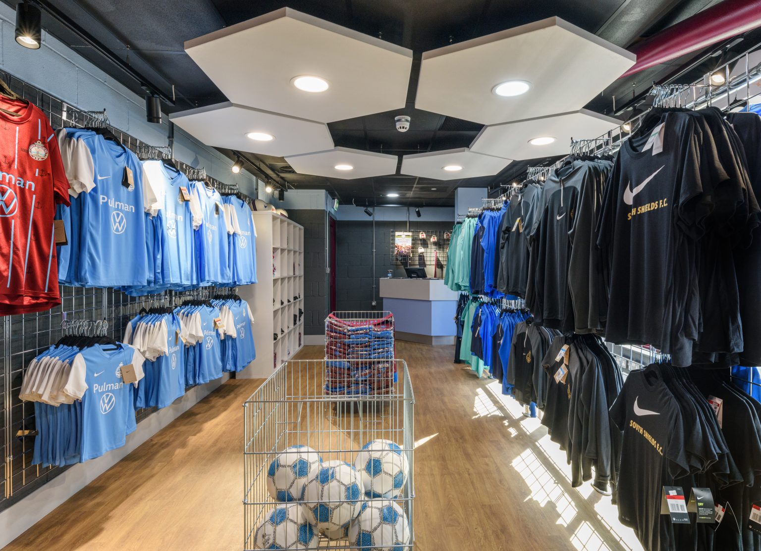 Hexagonal ceiling rafts over the club shop with lighting set into the ceiling