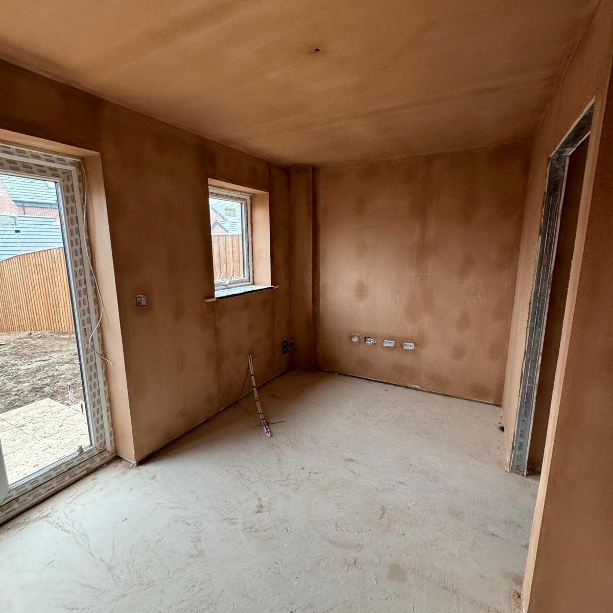 Freshly skimmed plaster walls and ceiling drying in a new build room