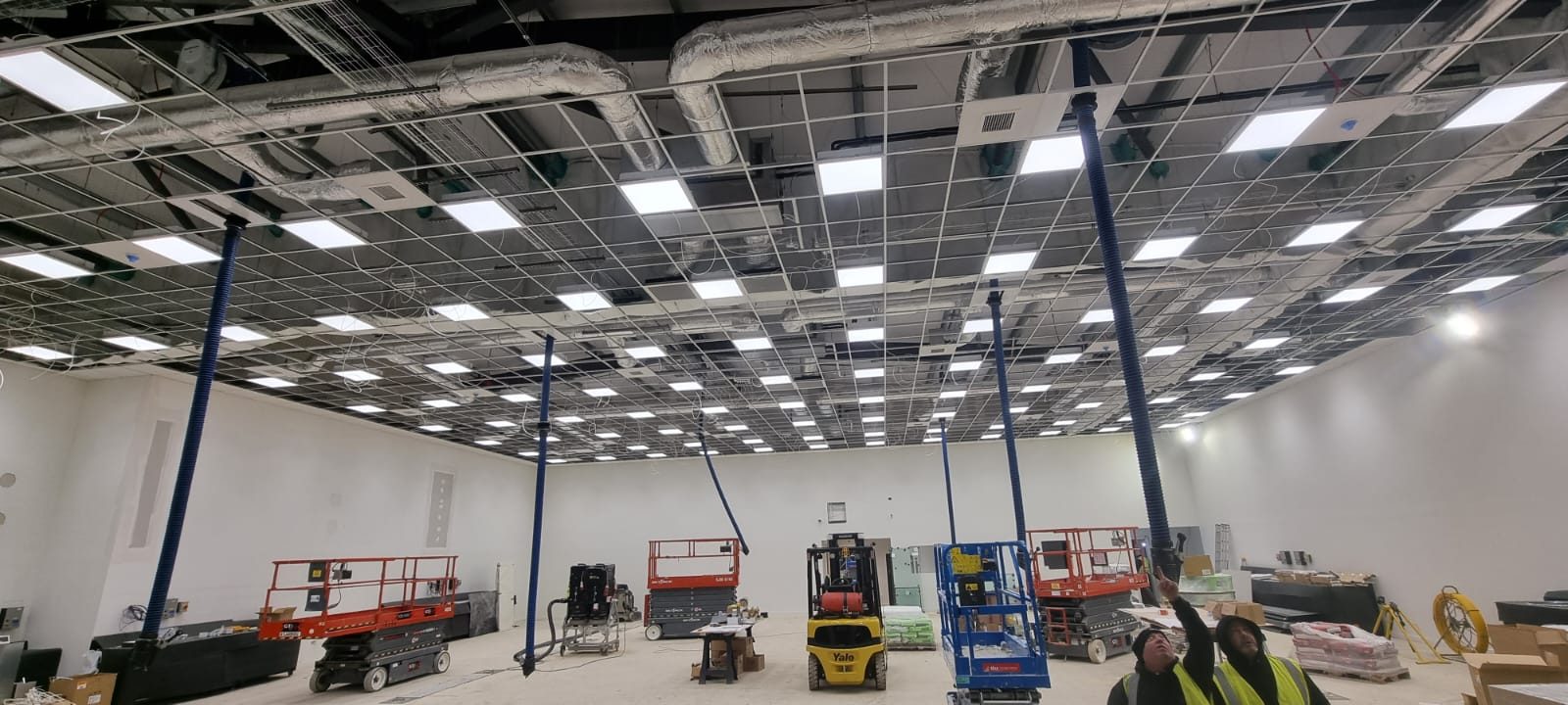 Suspended ceiling grid going in under exposed ductwork, with the lights fitted and the tiles still to come
