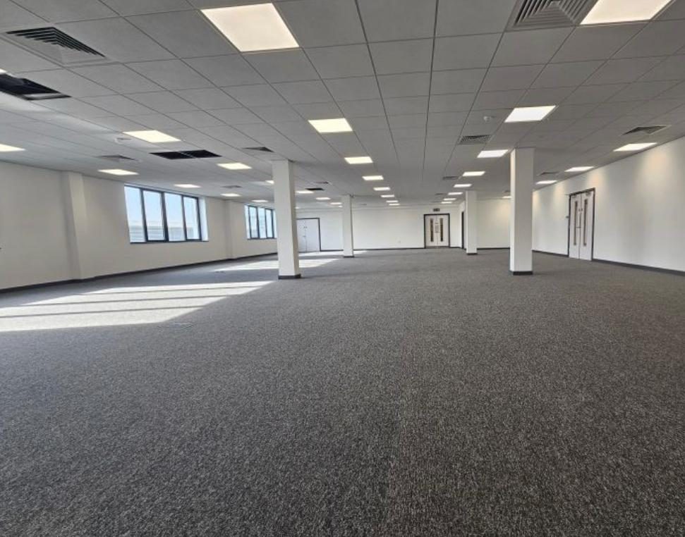 Open-plan office floor handed over under a suspended grid ceiling with LED panels