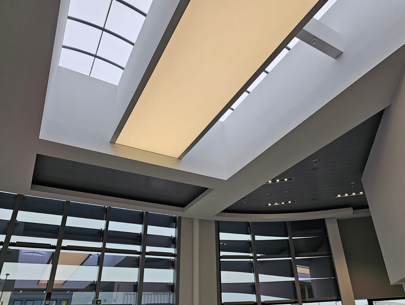 Feature bulkheads framing a rooflight and a lit ceiling panel above a glazed showroom front
