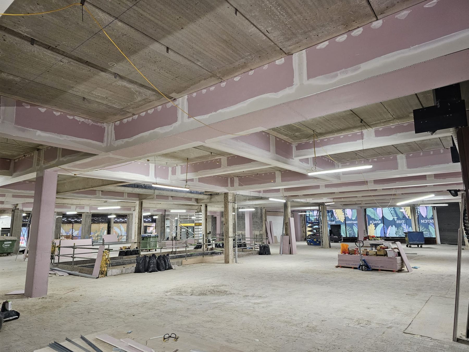 Fire-rated board encasing beams and columns across a shop floor refurbishment