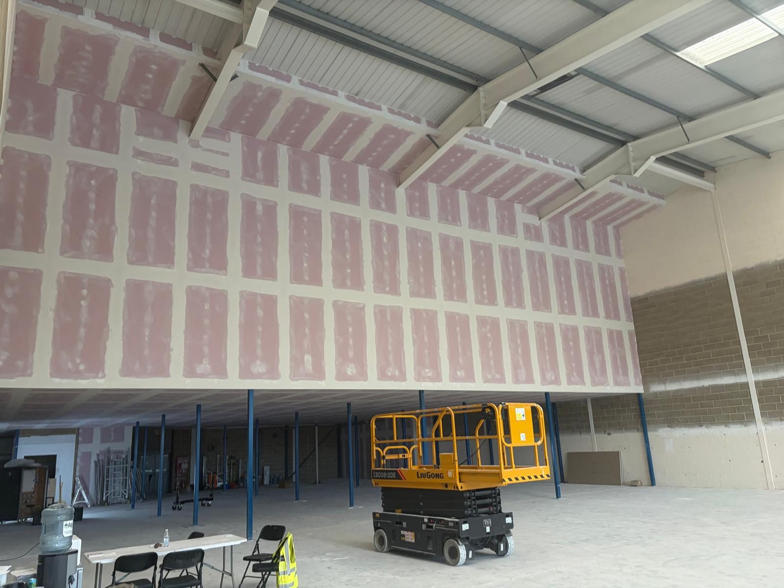 High-level partition in fire-rated board, taped and jointed up to the roof steels, above a mezzanine
