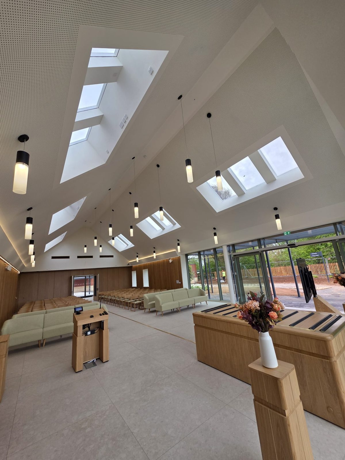 Finished hall under a vaulted plasterboard ceiling with rooflights and pendant lighting